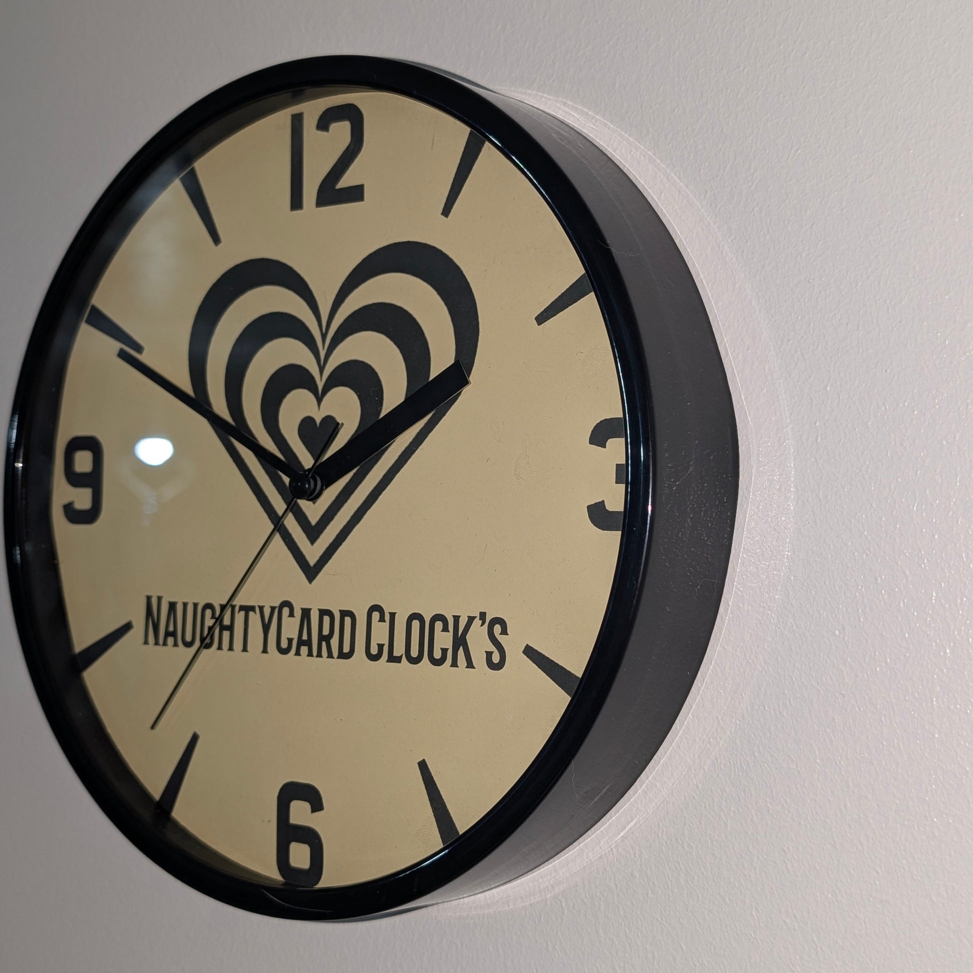 Right side view of black plastic wall clock from NaughtyCard - Value clock on plain wall