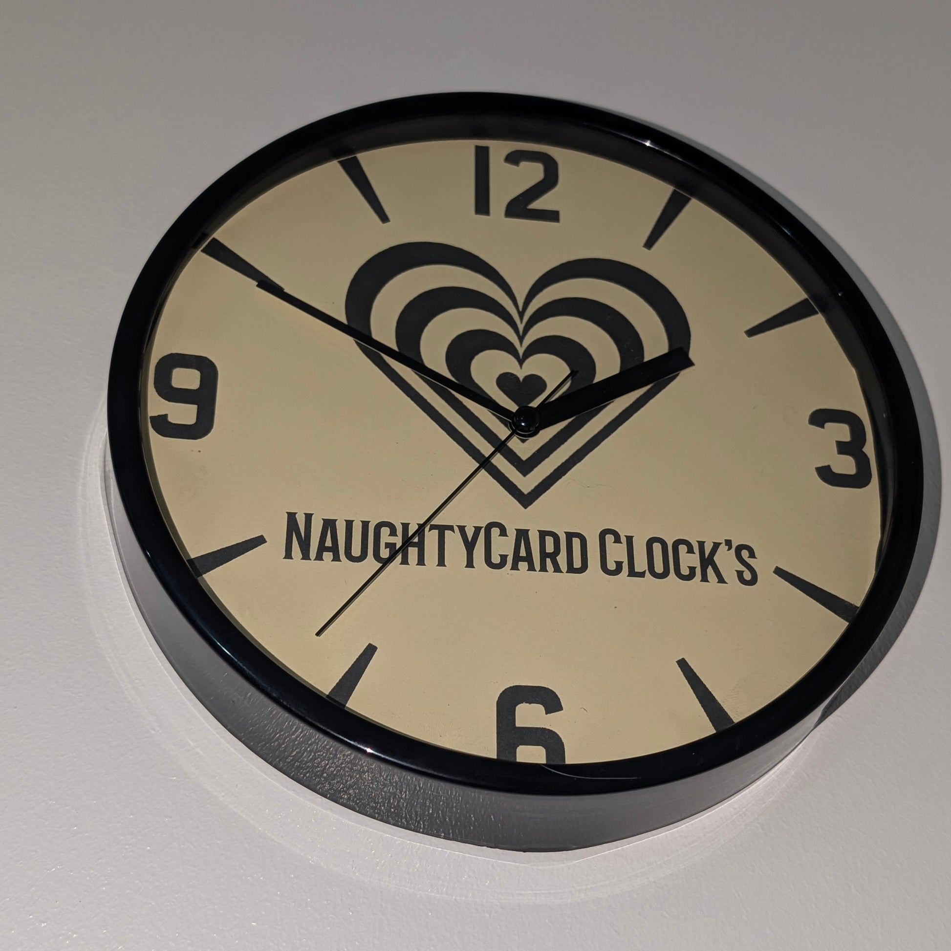 Bottom view of black plastic value wall clock from NaughtyCard, on a plain white background. Showing the clock from all angels.