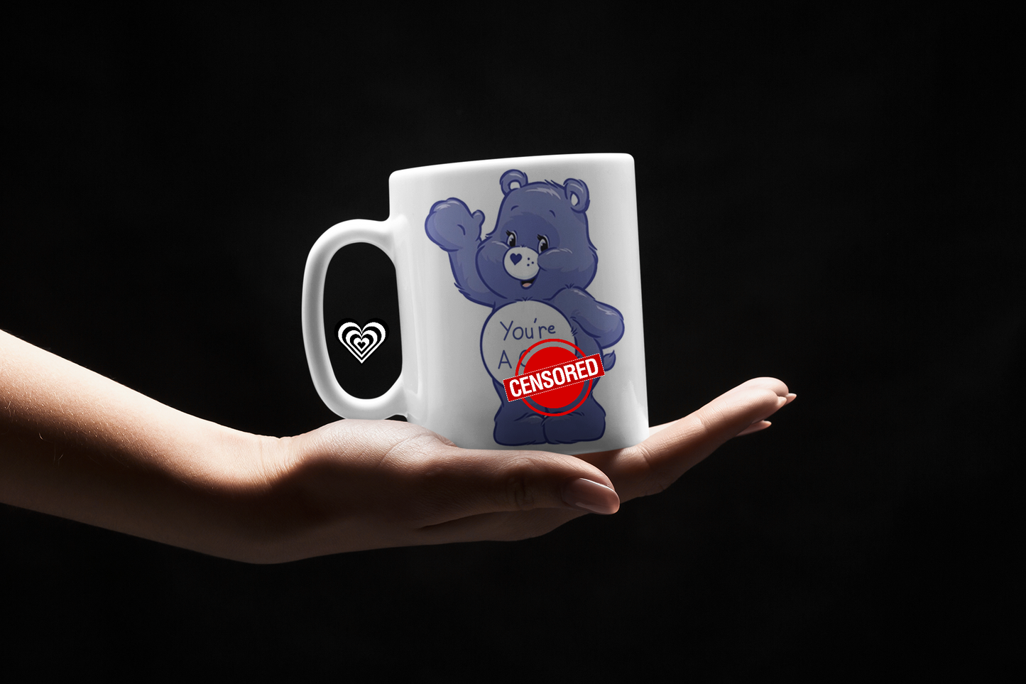 Mug with a blue bear graphic and text held by a hand against a black background