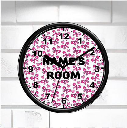Wall clock with pink bow pattern "Names Room" on a white brick wall background