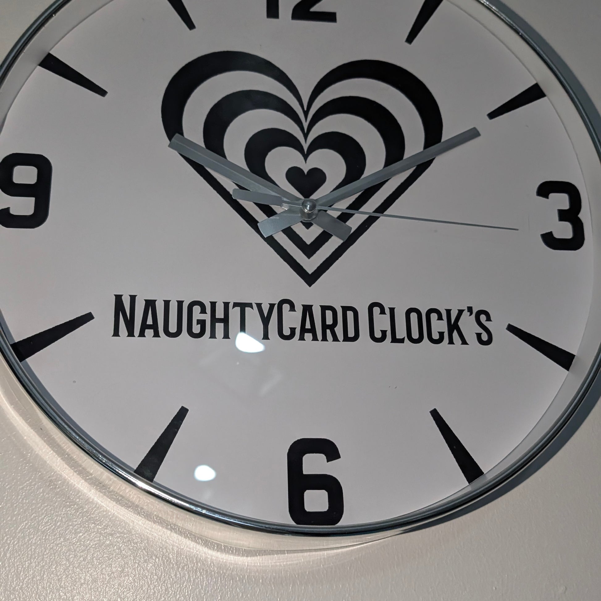 Silver Clock with heart design and 'NAUGHTYCARD CLOCK'S' text on a white background